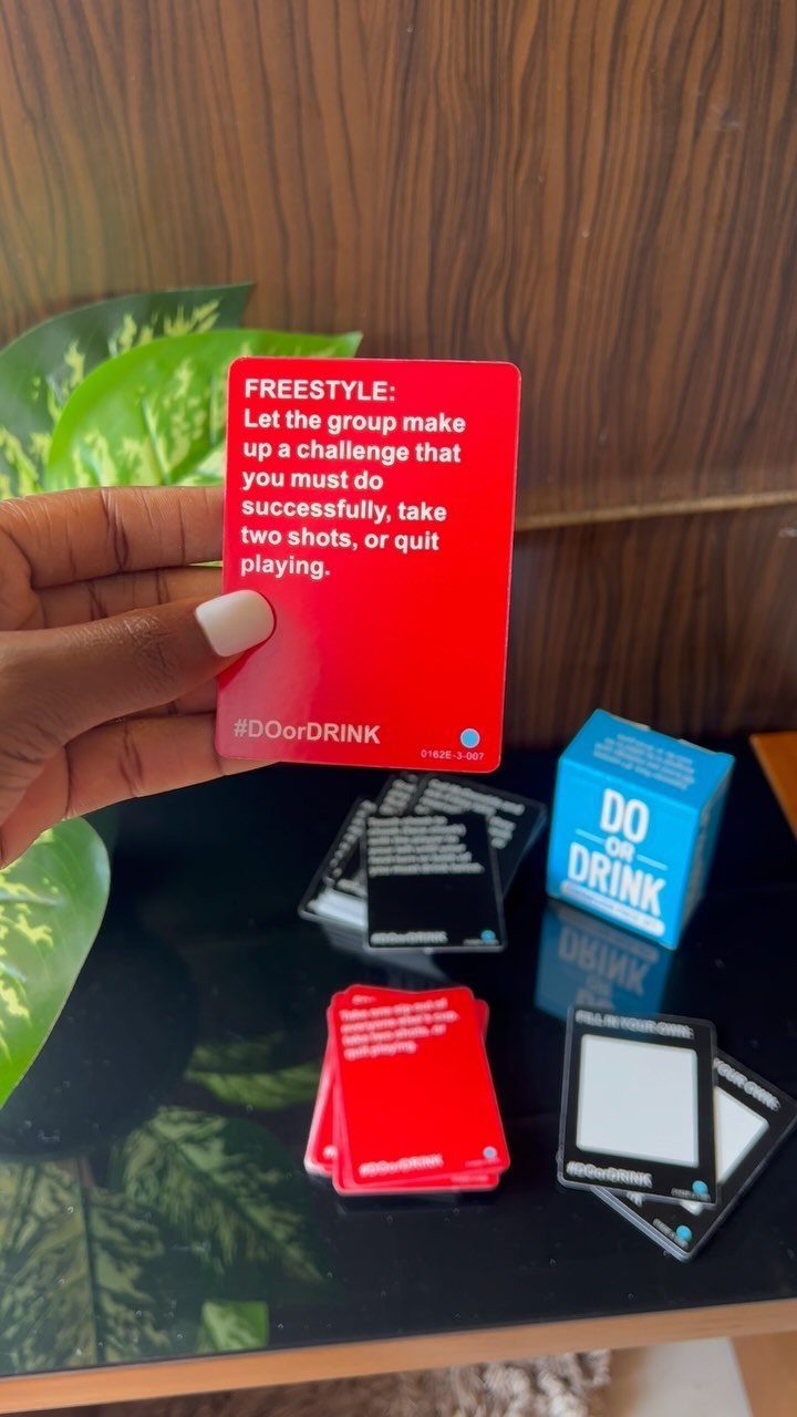 Hand holding a red game card from the Do or Drink party game.