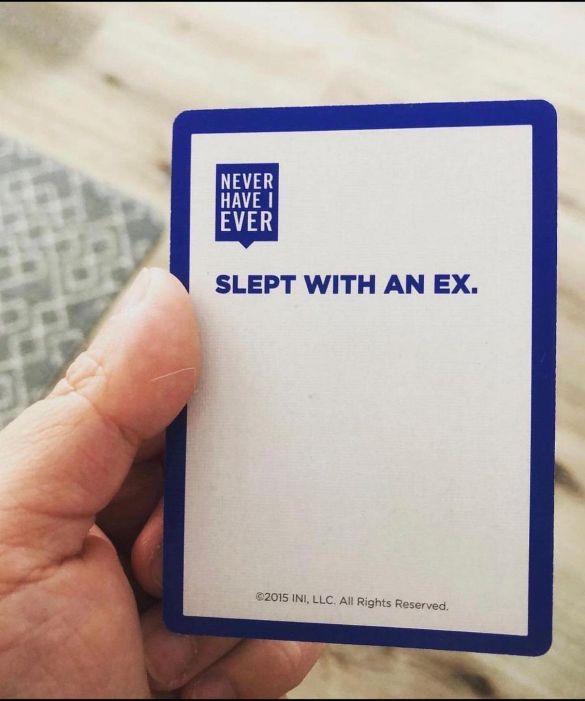 Hand holding a Never Have I Ever game card with a revealing prompt.