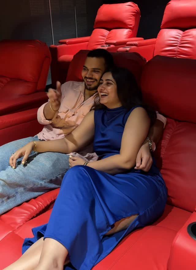 Couple smiling and laughing while sitting in red leather cinema seats in a theater