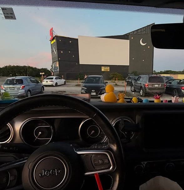 Drive-in movie screen viewed from the interior of a parked Jeep vehicle.