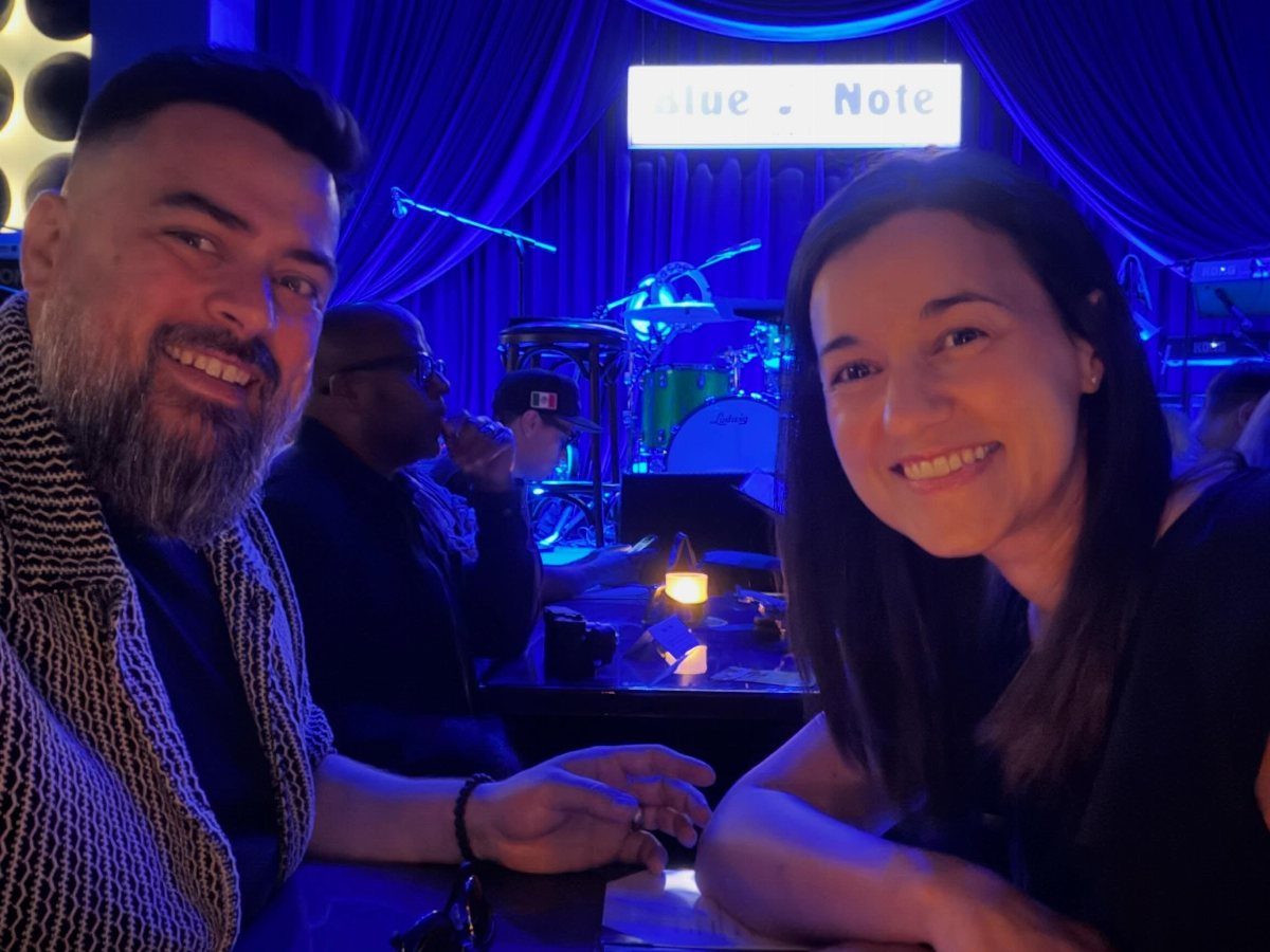 Smiling couple at a jazz club with a live saxophone player in background