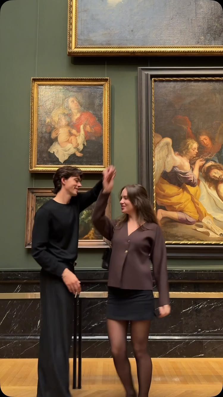 Couple dancing in an art gallery in front of classical oil paintings.