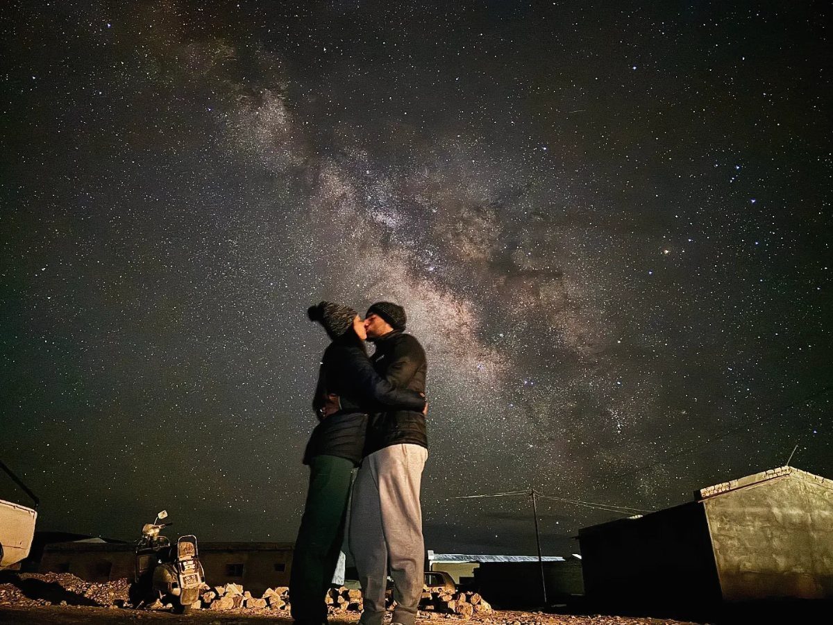 Couple kissing under a brilliant starry night sky with the Milky Way visible.