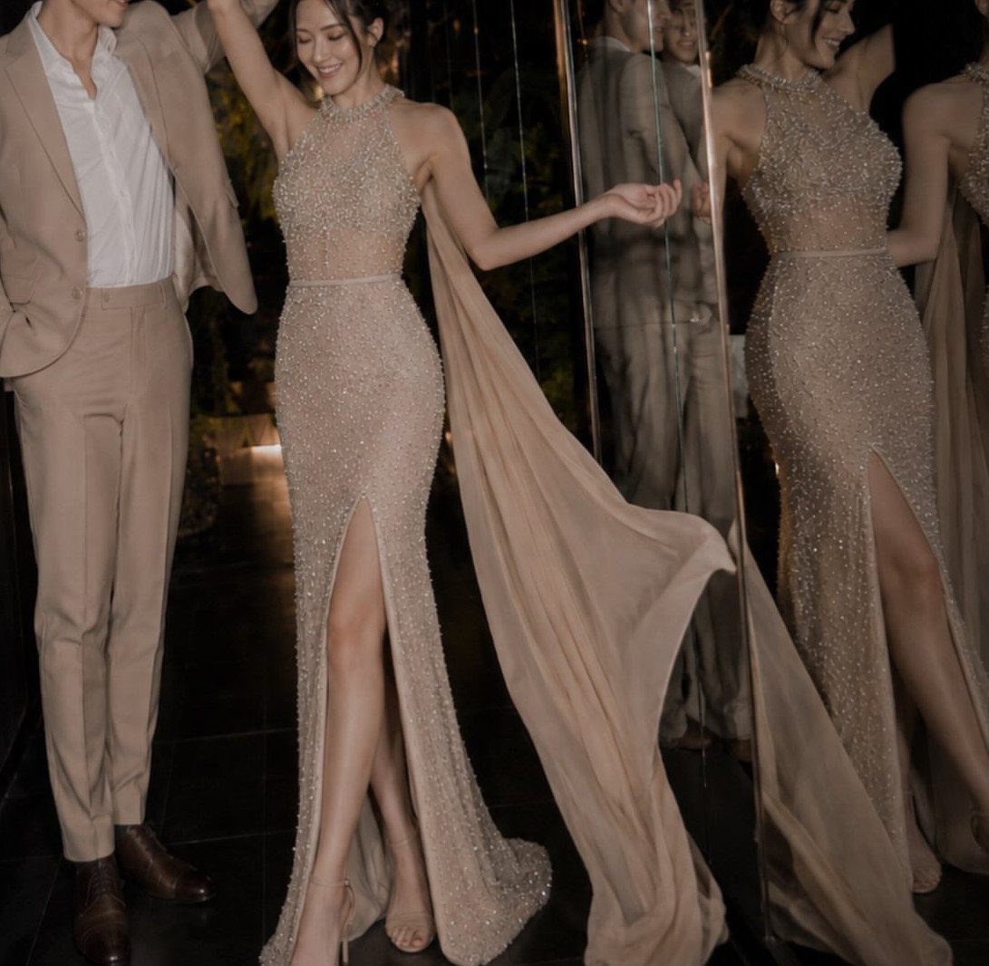 Woman in a shimmering champagne designer layered dress with a man in tan suit.