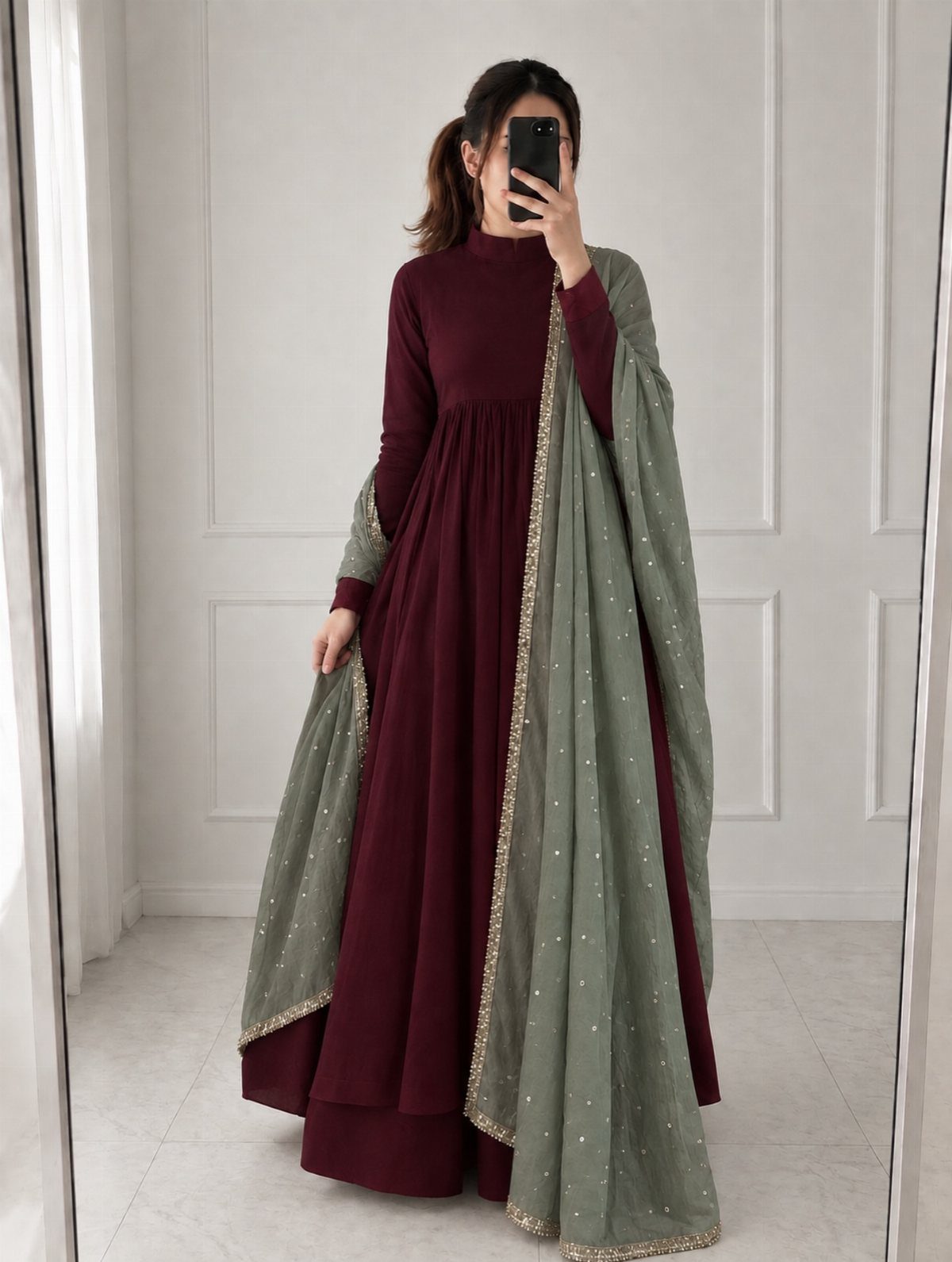 Woman in a ruby red floor-length gown with a sage green embroidered dupatta.