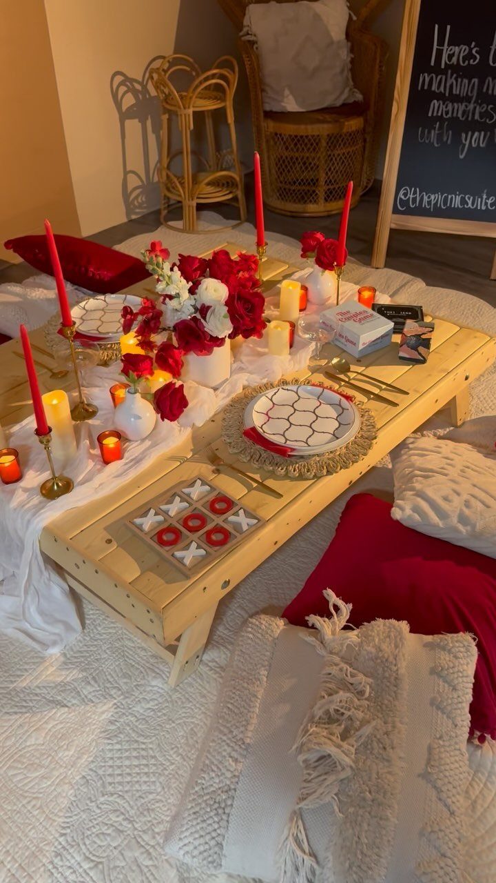 Low wooden table with red roses and candles set on a white rug.