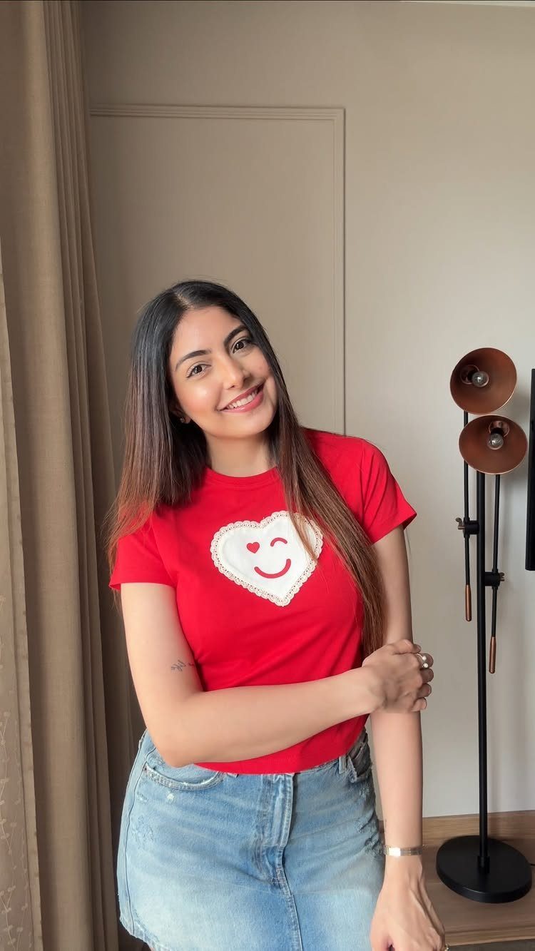 Woman wearing a red graphic t-shirt with a heart and blue jeans.