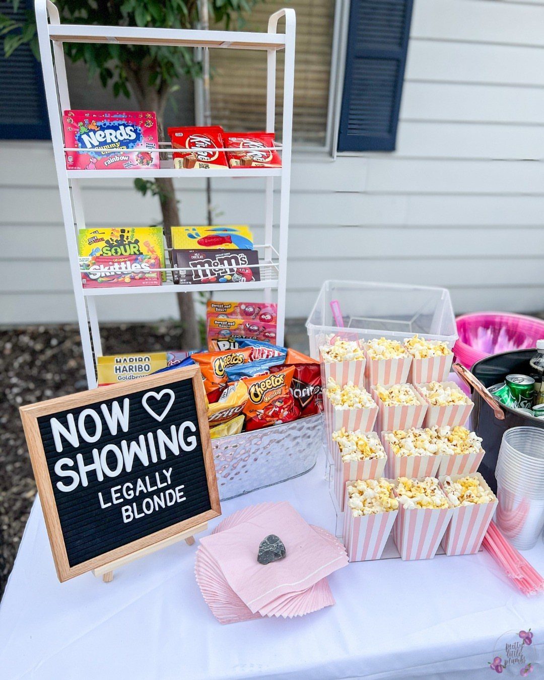 Snack bar with popcorn, candy, and chips next to a movie sign.