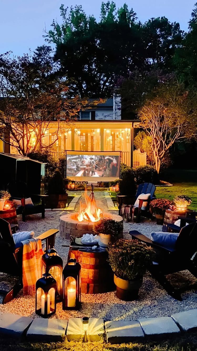 Outdoor movie screen and fire pit with cozy seating in a backyard at dusk