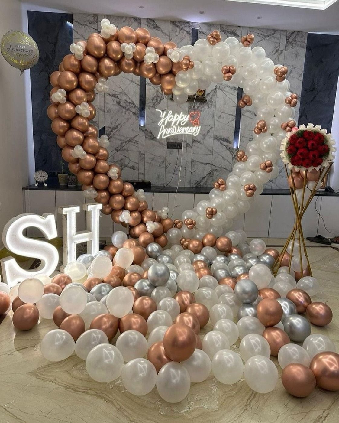 Heart-shaped balloon arch in rose gold and white for an anniversary celebration.