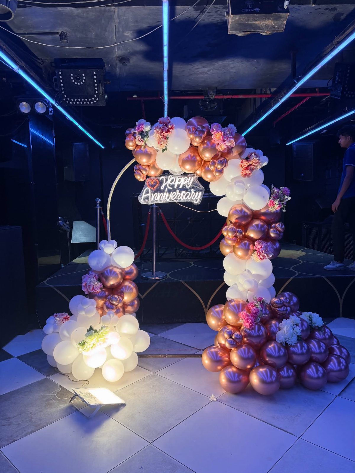 Rose gold and white balloon garland arch with Happy Anniversary neon sign.