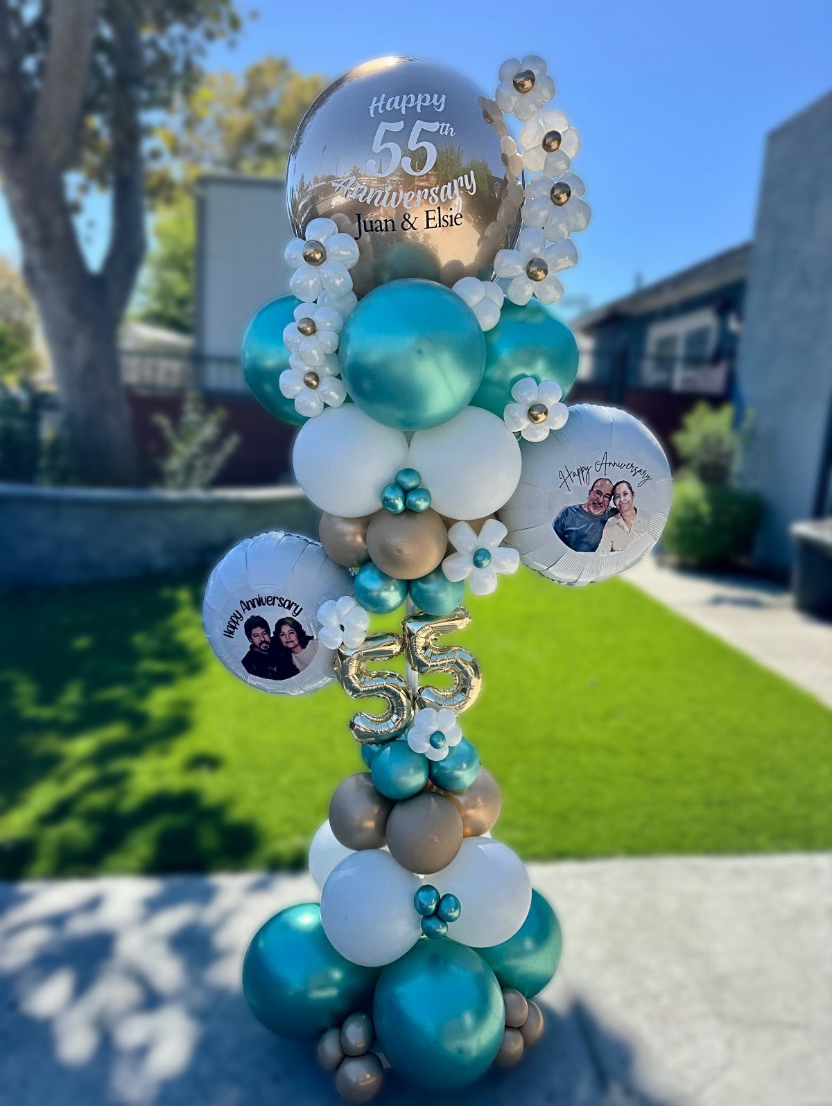 Balloon tower with teal and gold balloons, personalized names, and anniversary photos.