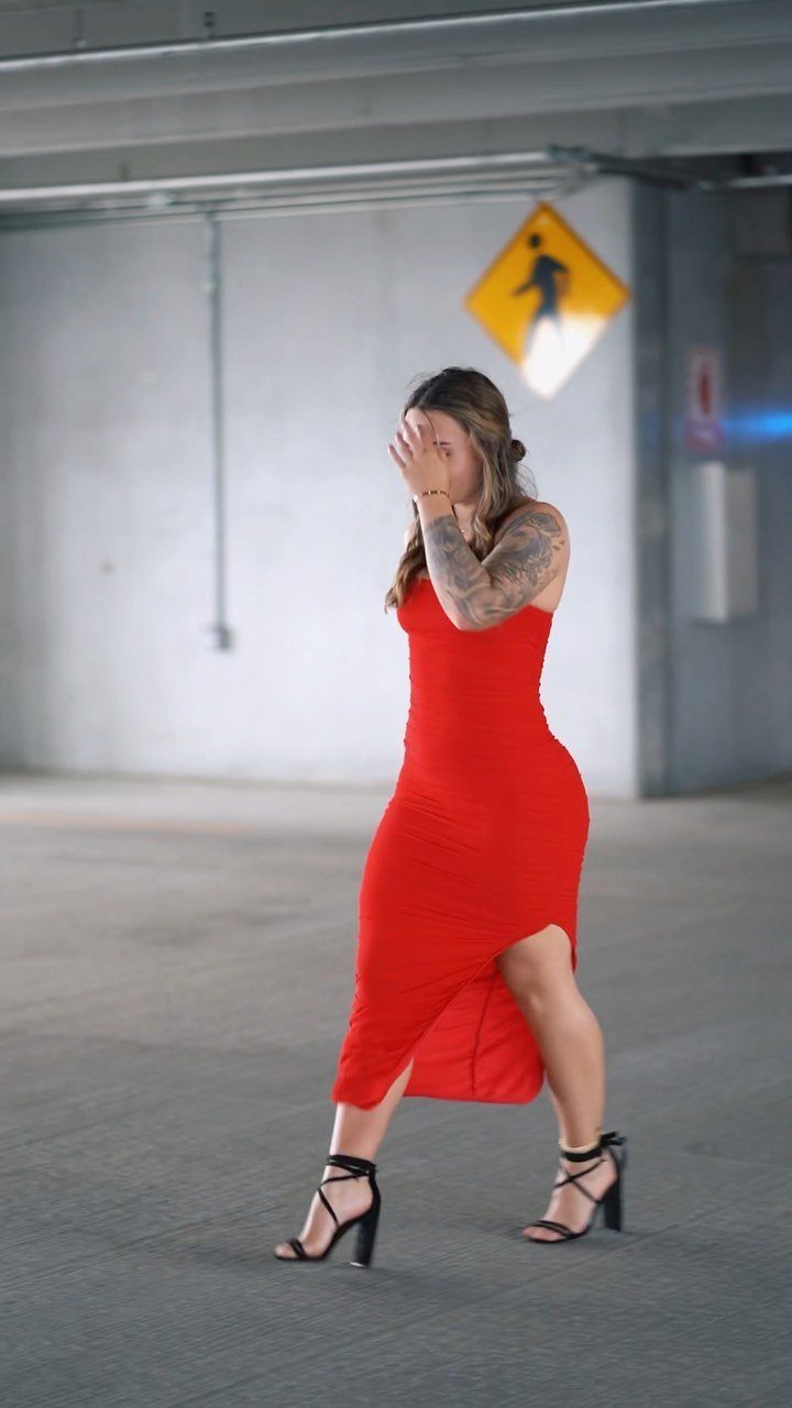 Woman in a red sleeveless midi dress and black heels in a parking garage
