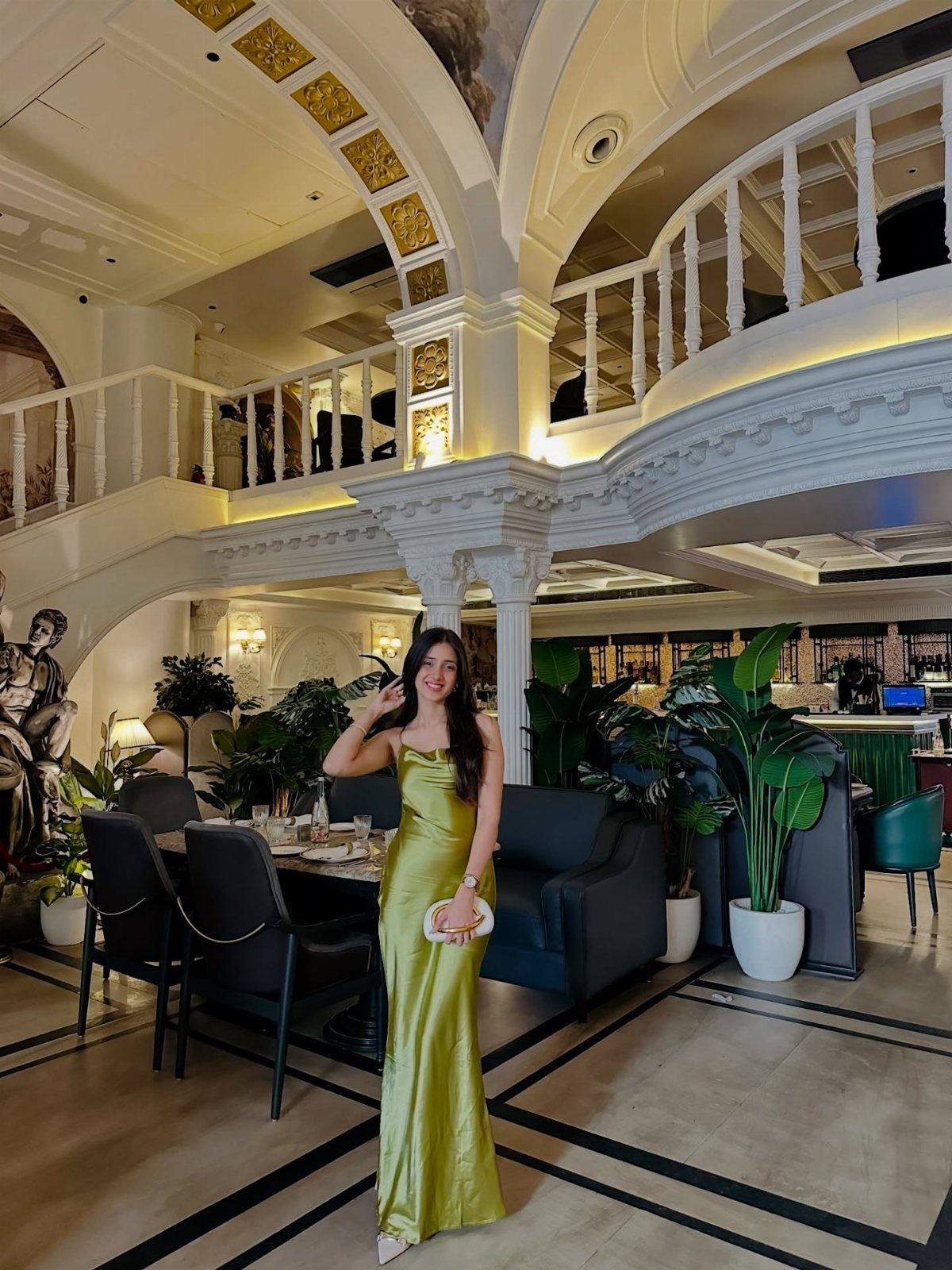 Woman in a lime green satin maxi slip dress posing in a luxury interior