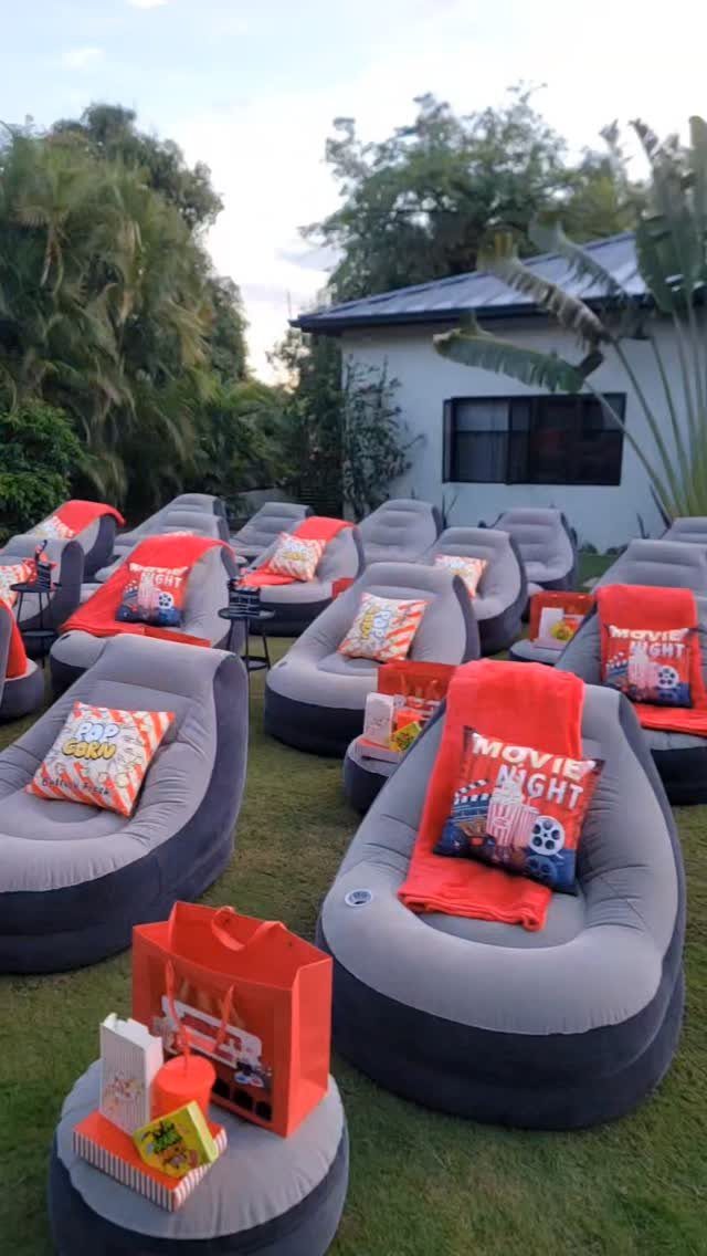 Inflatable lounge chairs with popcorn pillows and red blankets set up outdoors.