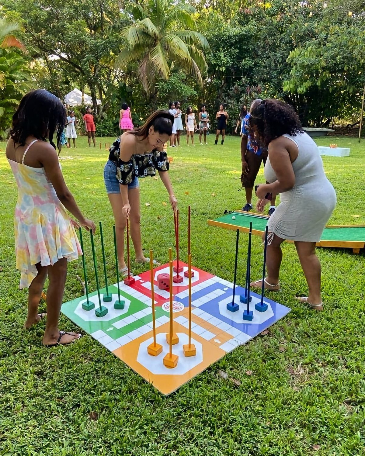Women playing a giant colorful board game on a grassy outdoor lawn