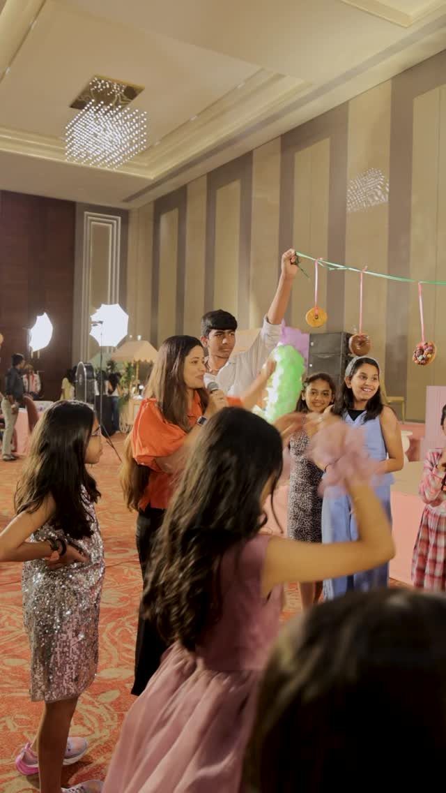 Children playing a donut hanging game at a birthday party in a hall