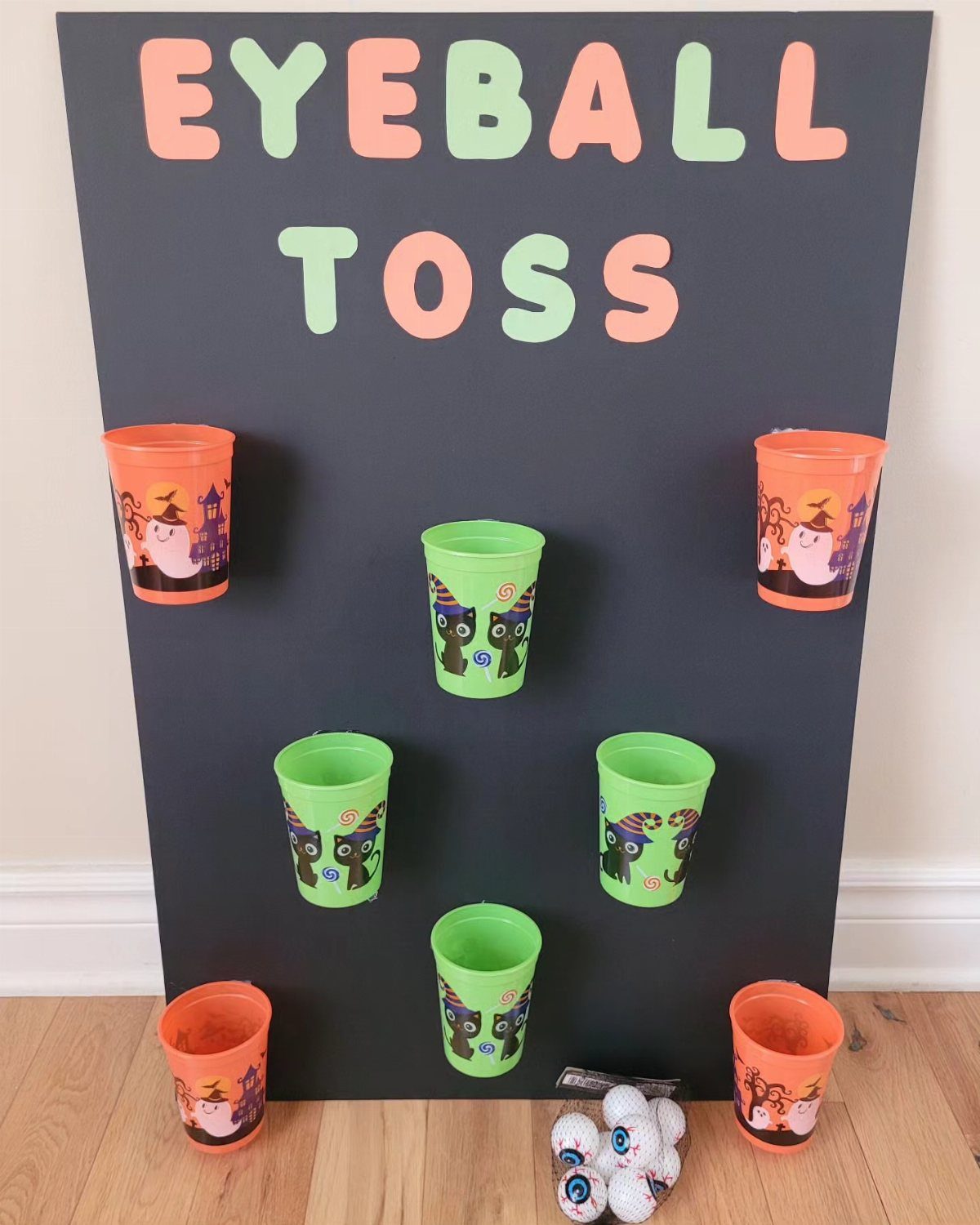 Eyeball toss game board with colorful plastic cups and eyeball balls on floor