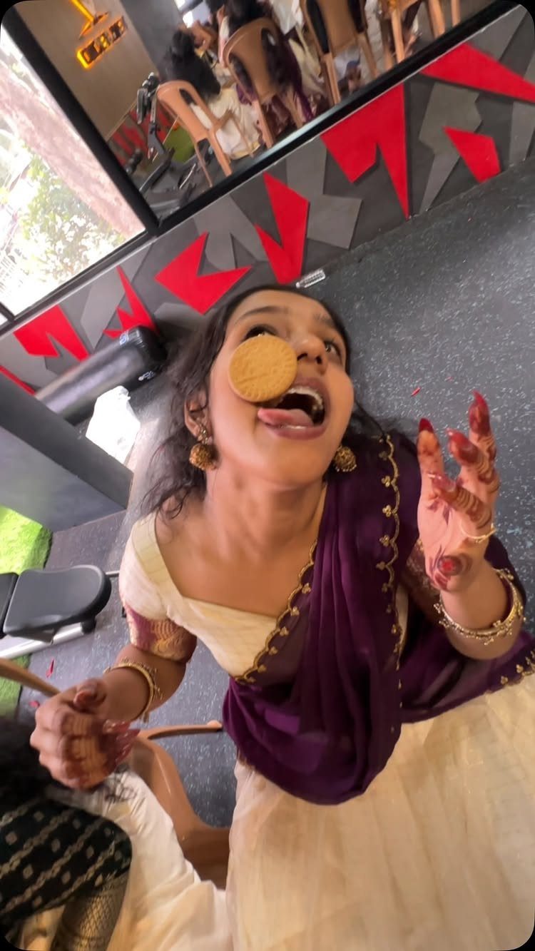 Woman in traditional Indian dress attempting to catch a cookie in her mouth.