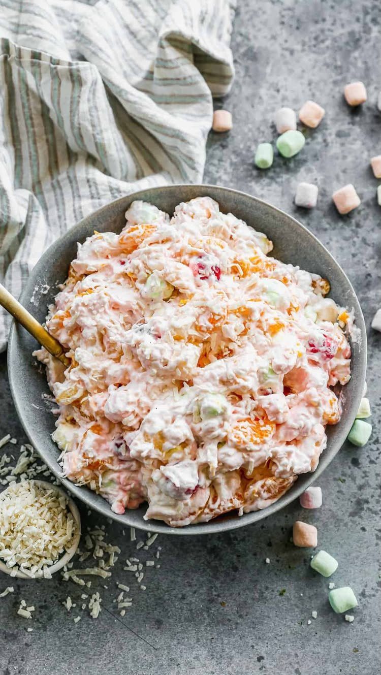 Ambrosia salad with colorful marshmallows in a grey bowl on a stone surface.