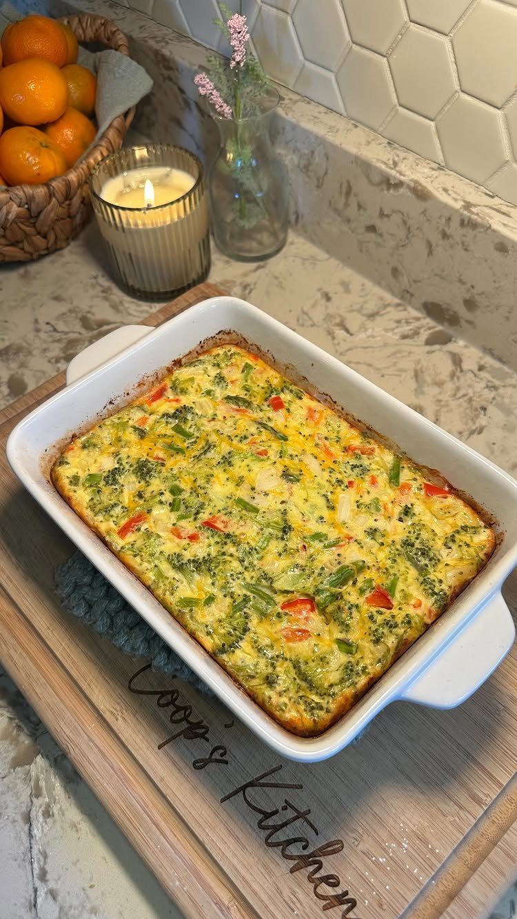 Baked egg casserole with broccoli and red peppers in a white ceramic dish.