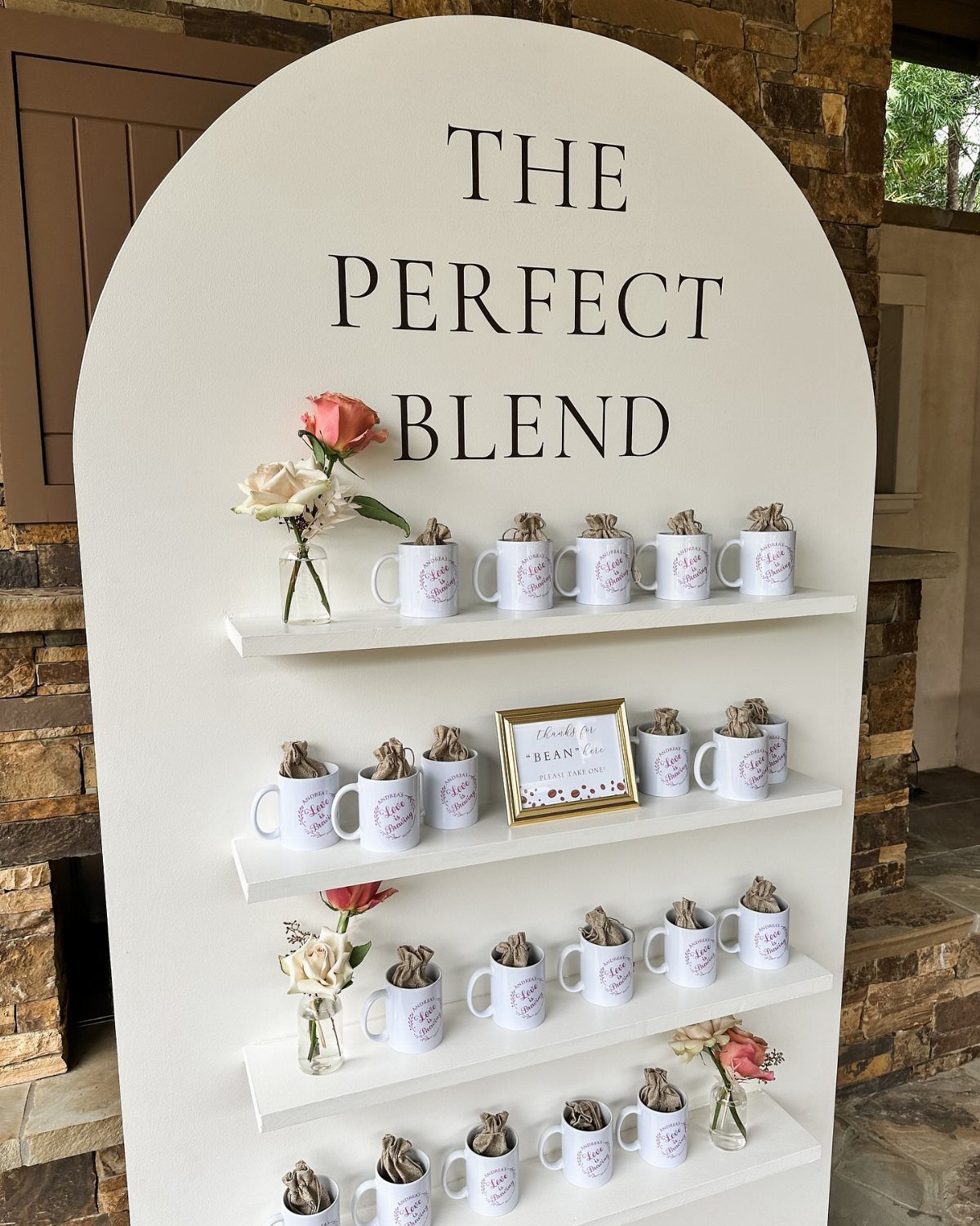 White arched backdrop with coffee mugs and roses for a bridal shower theme.