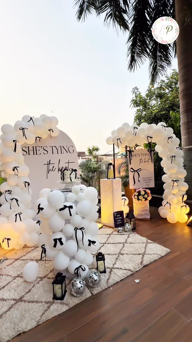White balloon arches with black bows and a sign saying She's Tying the Knot.