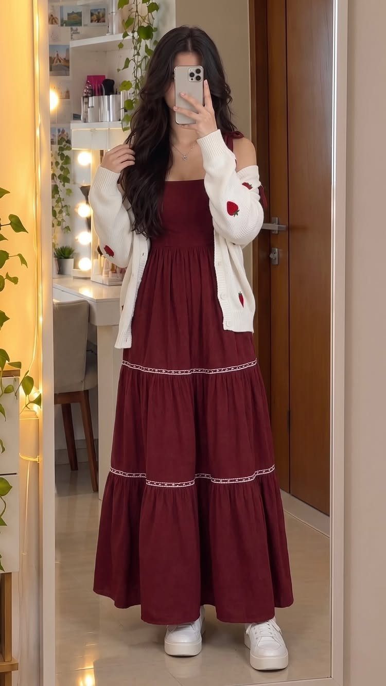 Woman wearing a tiered burgundy maxi dress with a white strawberry print cardigan.