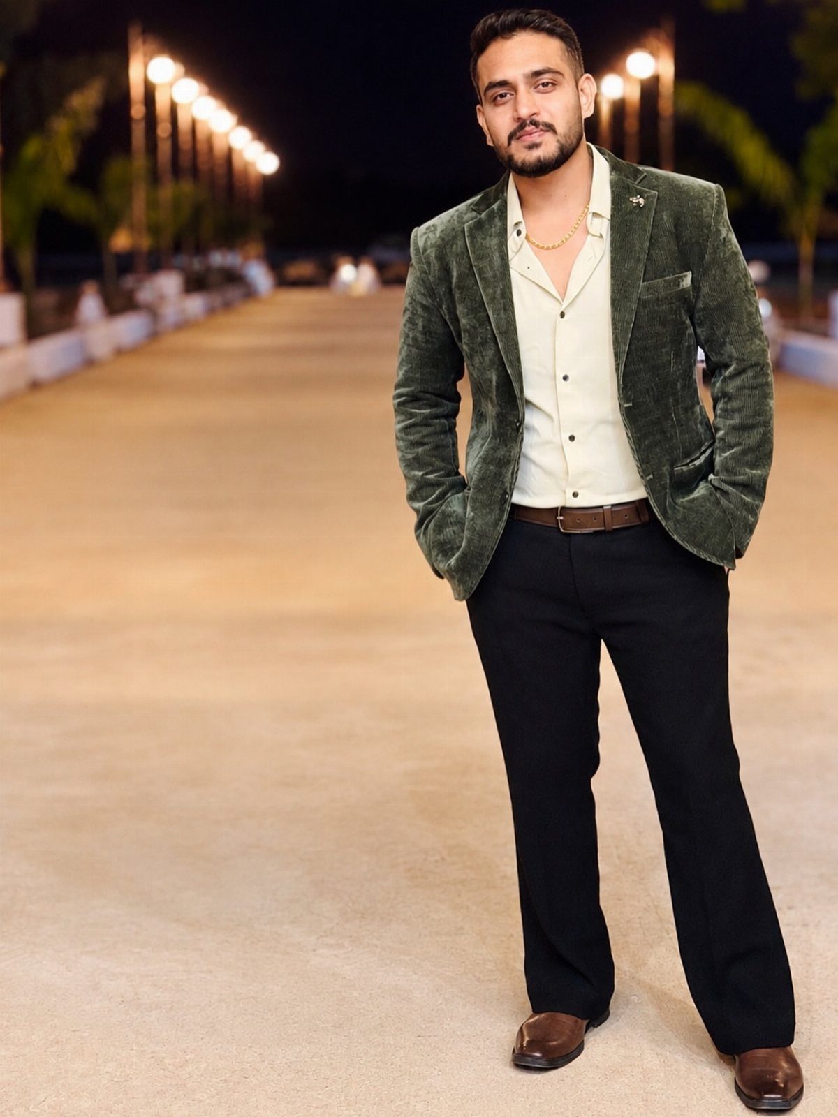 Man wearing a green velvet blazer with a white shirt and black trousers.