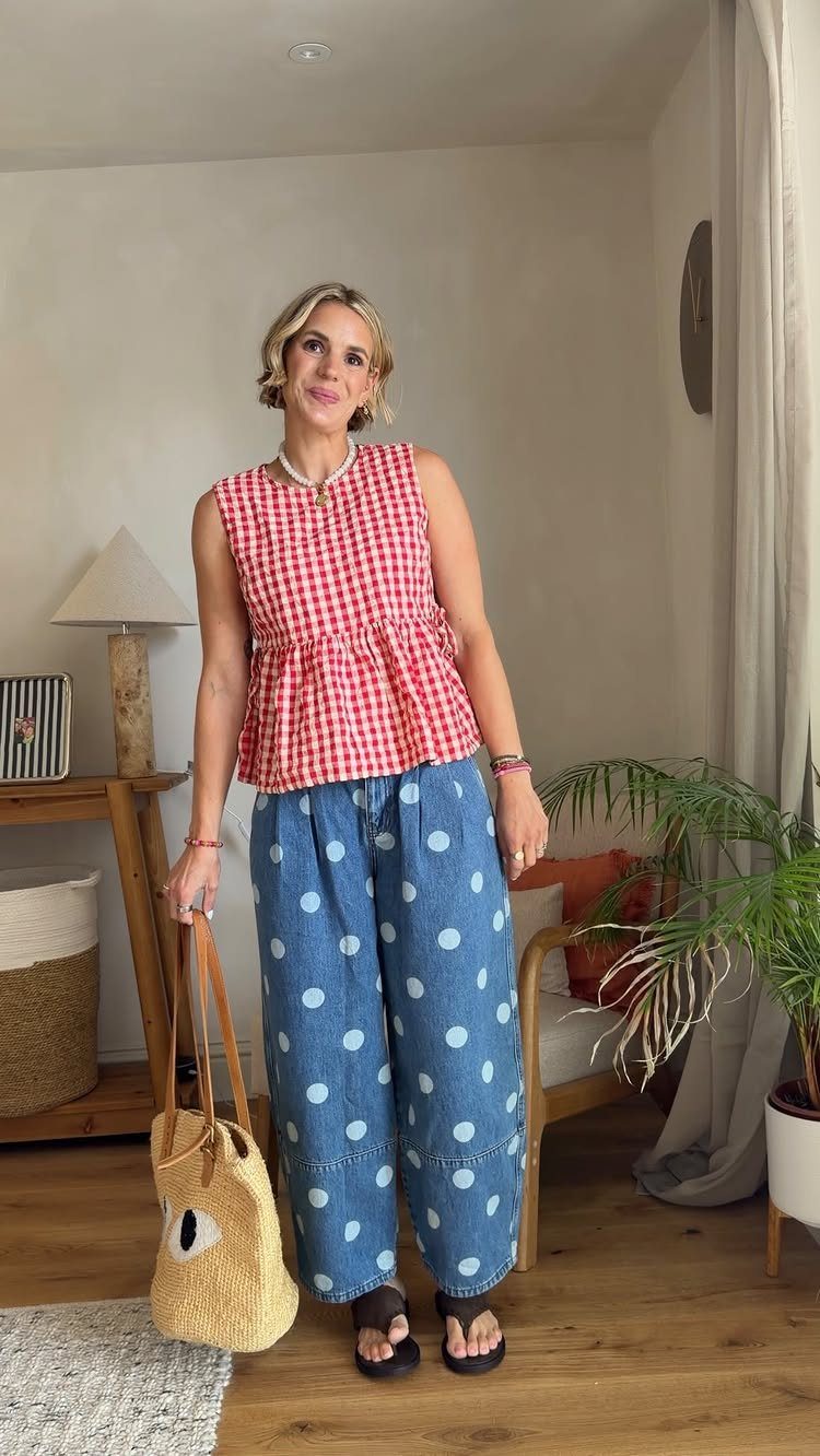 Woman wearing polka dot wide-leg jeans and a red gingham top indoors.