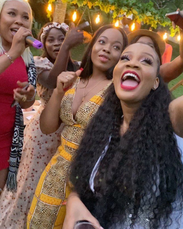 Women singing and laughing with a microphone during an outdoor karaoke party night.