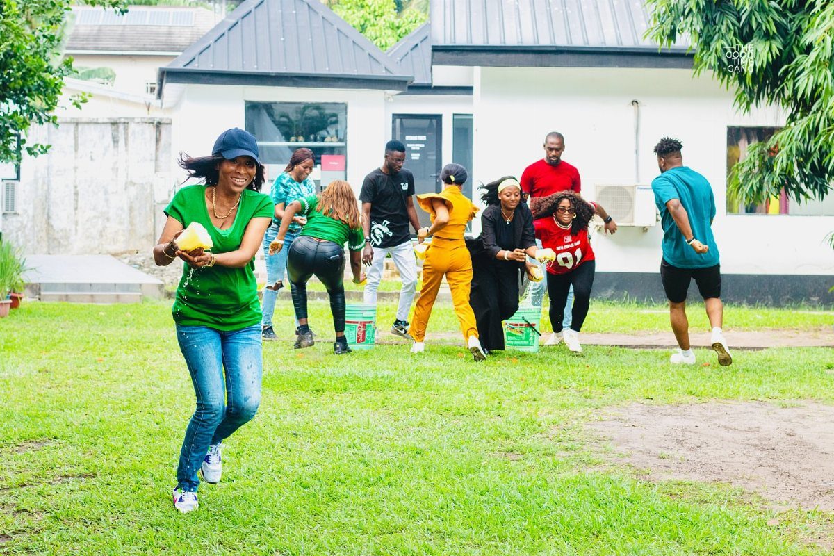 Adults playing an active outdoor game on a grassy lawn during a celebration.