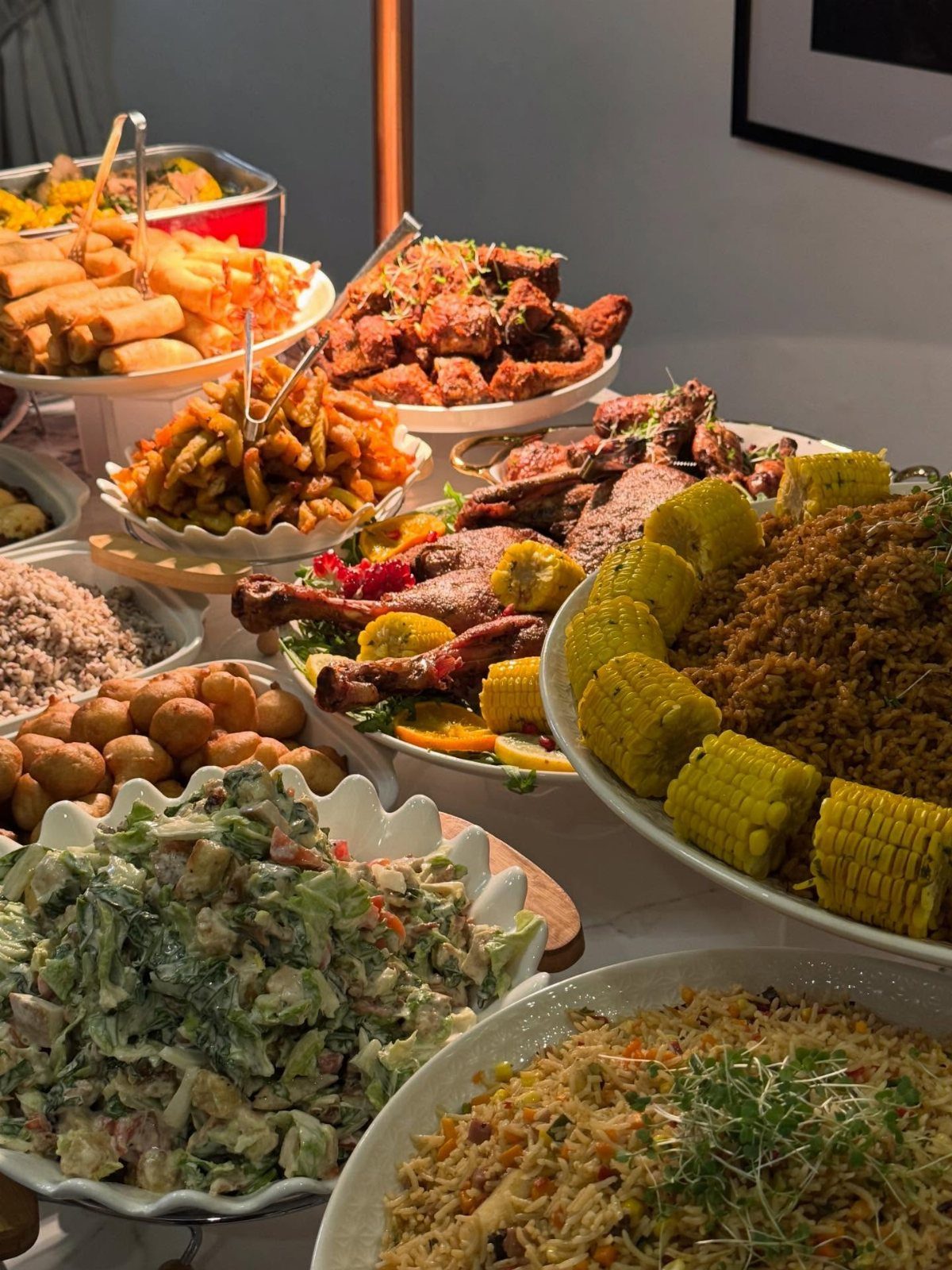 Assorted buffet dishes including fried chicken, corn, and salads on a white table.