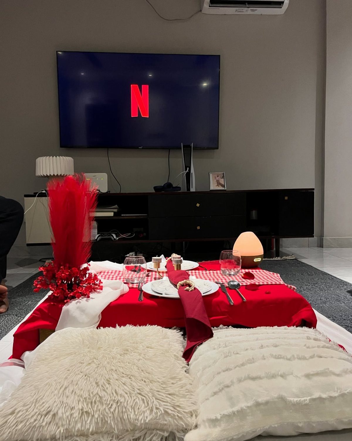 Indoor picnic setup with red linens, white pillows, and a Netflix screen background.