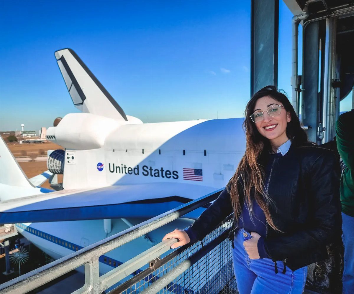 Woman smiling in front of a NASA space shuttle at Space Center Houston.