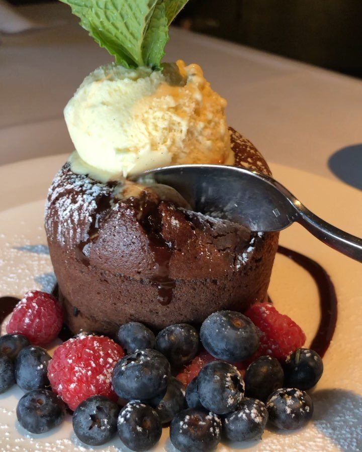 Chocolate lava cake topped with vanilla ice cream, mint, and fresh mixed berries.