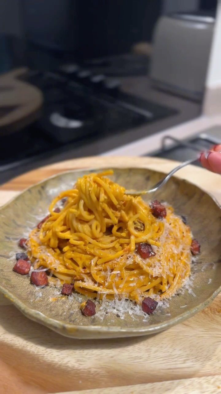 Creamy pasta carbonara with pancetta and grated cheese in a rustic bowl.