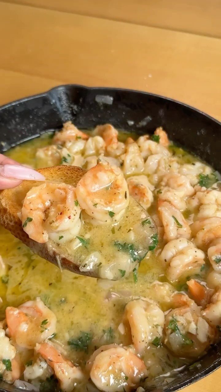 Shrimp scampi in a cast iron skillet with a piece of toasted bread.