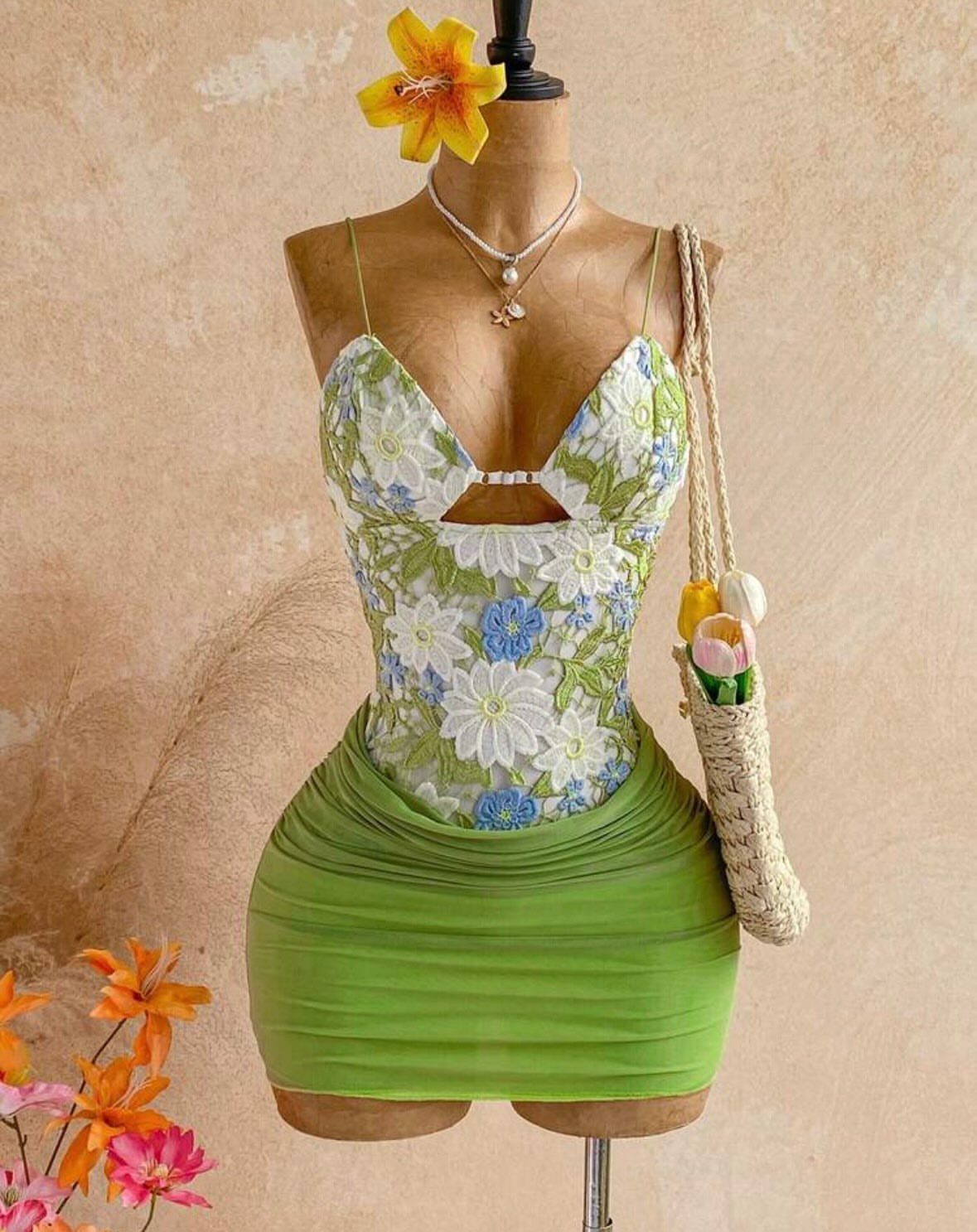 Floral print bodice and green mini skirt on a mannequin with straw bag.