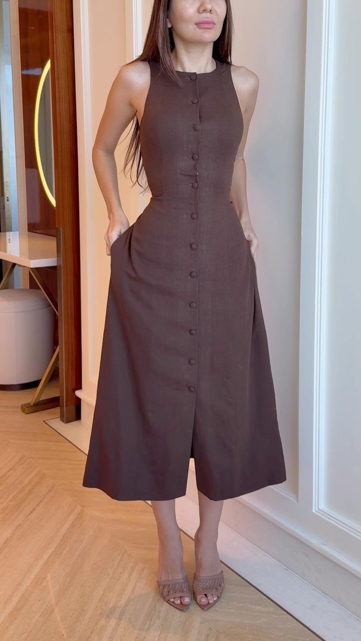 Woman wearing a sophisticated brown button-down midi dress and beige open-toe heels.
