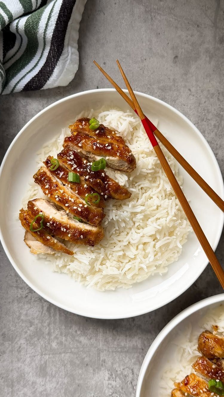 Glazed chicken breast with sesame seeds and green onions over white rice.