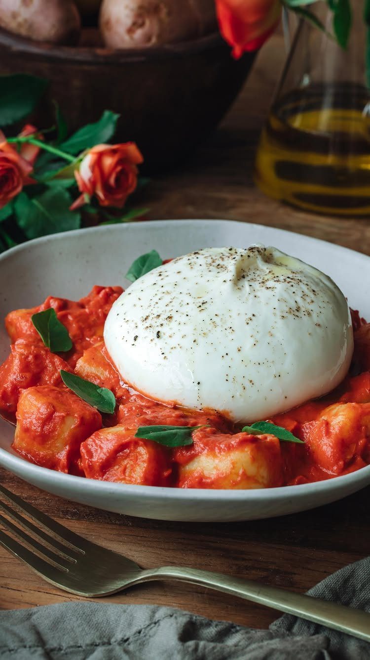 Potato gnocchi in red sauce topped with a large ball of burrata cheese.