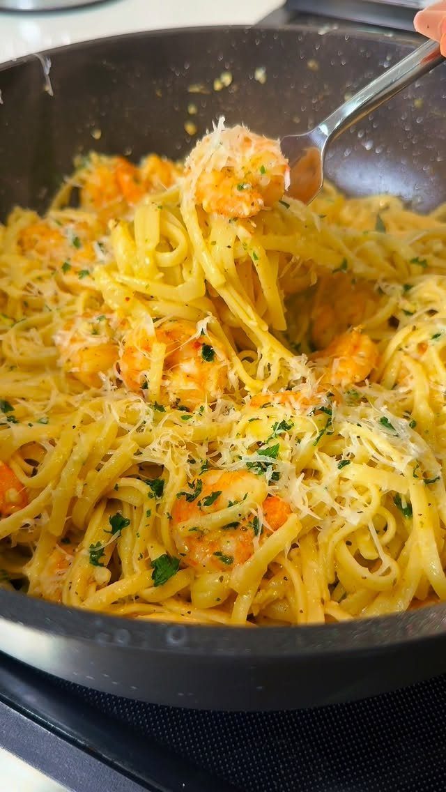 Shrimp scampi pasta with parmesan and parsley in a black cooking pan.