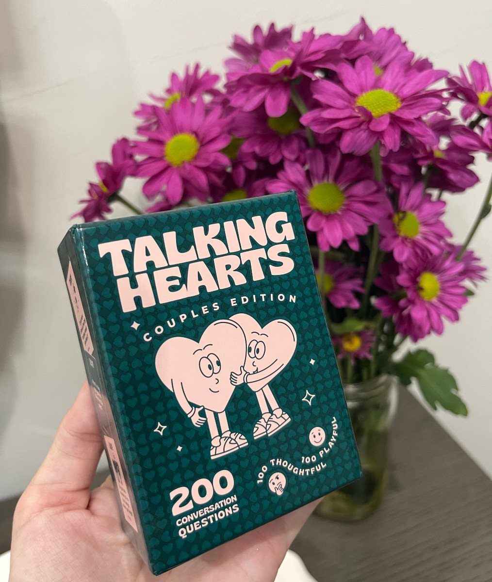 Talking Hearts Couples Edition card box held in front of purple daisies