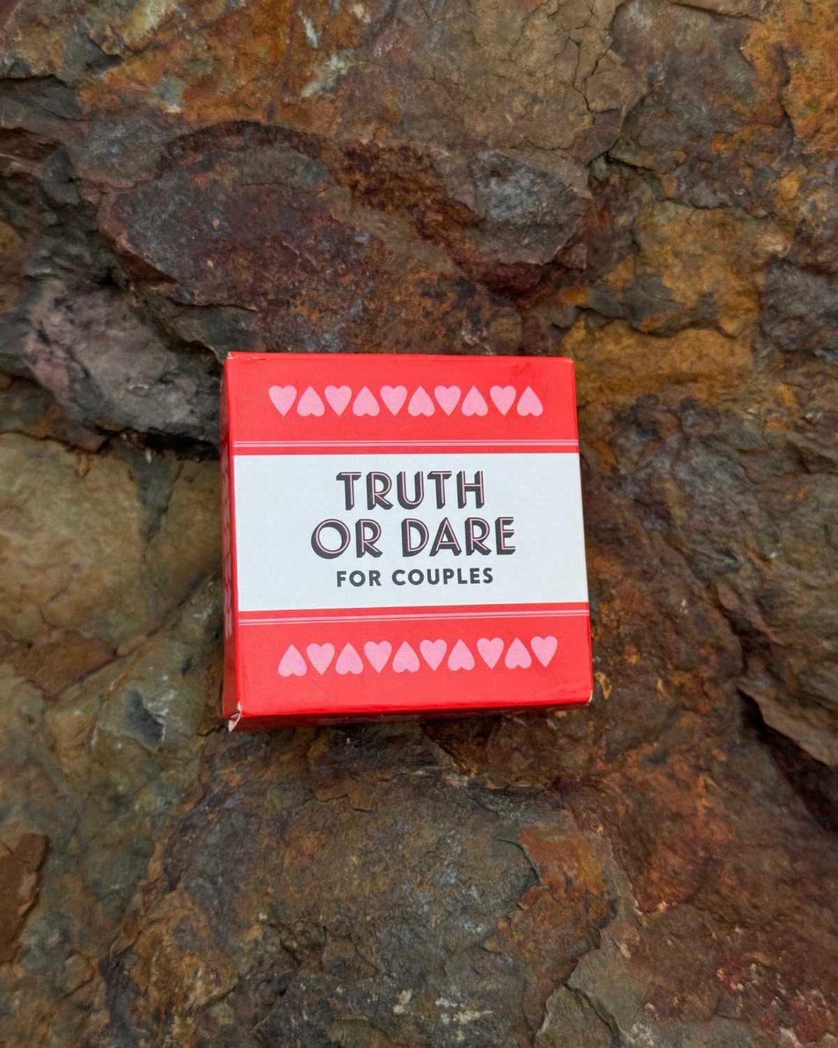 Truth or Dare for Couples game box resting on a textured rock surface.