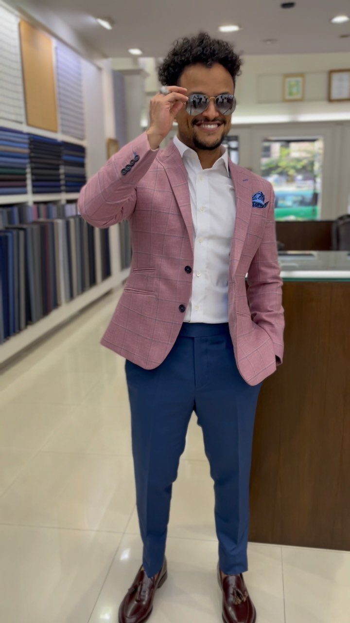 Man wearing a pink patterned blazer with navy blue chinos and brown shoes.