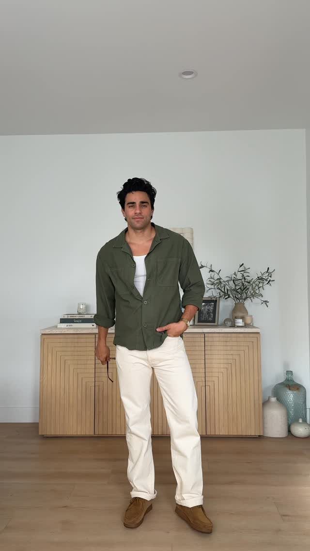 Man wearing olive green shirt, white t-shirt, and cream trousers for date night.