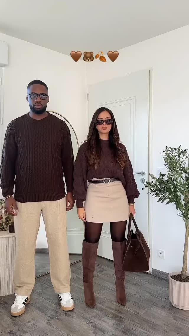 Man in brown sweater and cream trousers posing with woman in brown outfit.