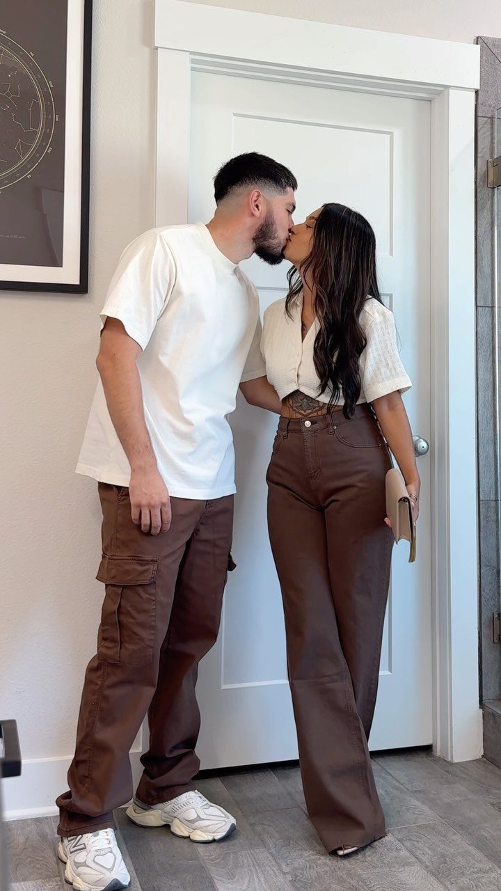 Couple kissing, woman wearing a white shirt and brown wide-leg trousers for a date.