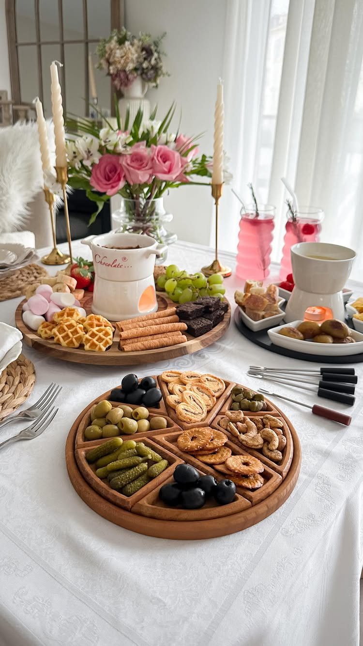 Romantic table setting with charcuterie boards, pink roses, and white candles on white cloth